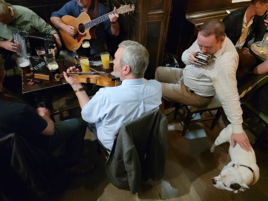 Harmonica player petting the bar dog at Sandy Bell's